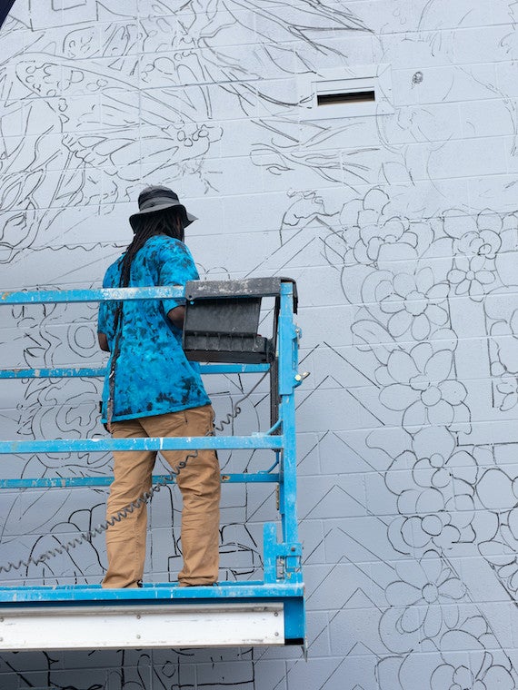 A man draws a mural design on a building.