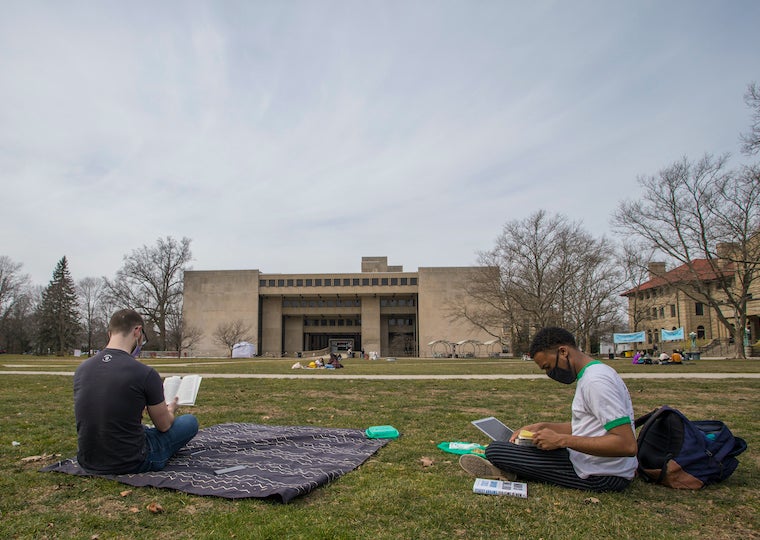 Two students sit on the grass and read.