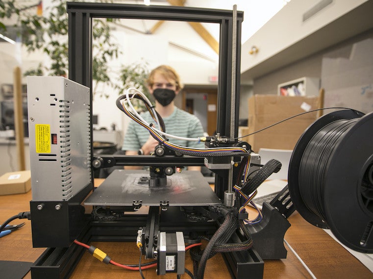 A student looks through a 3D printer.