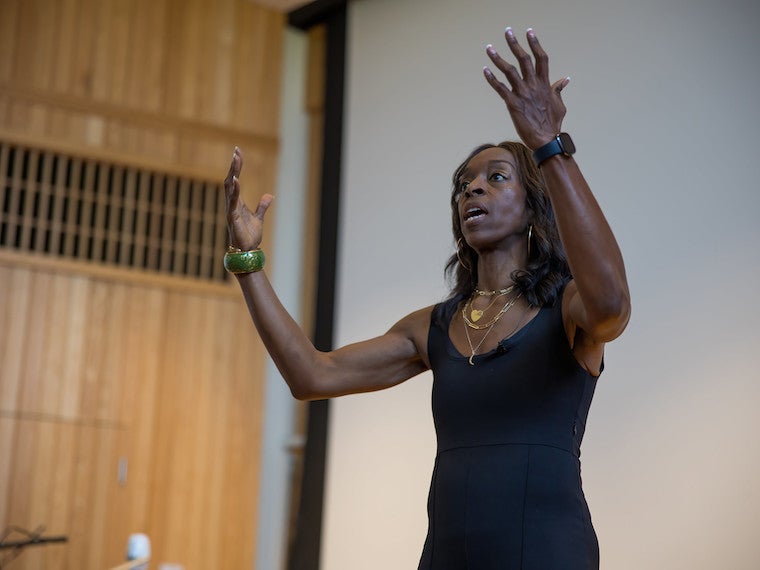A woman raises her hands passionately in front of an audience.