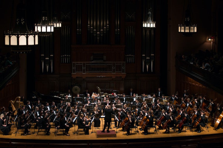 A large orchestra performs on stage