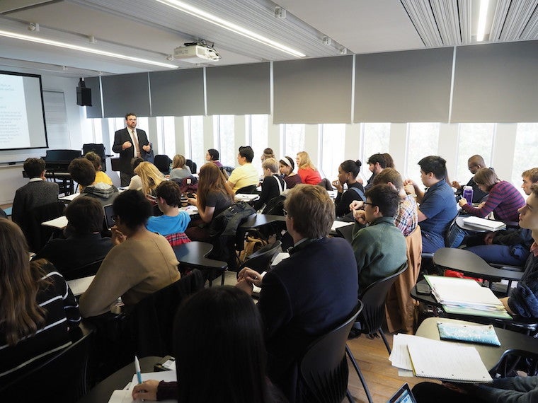 Students facing the teacher in a full classroom.