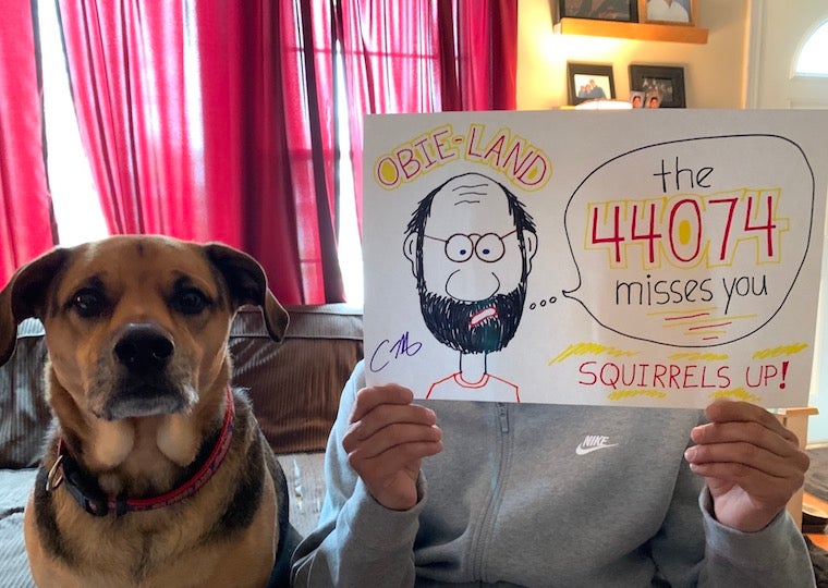 A man holds up a picture of himself with his dog sitting nearby