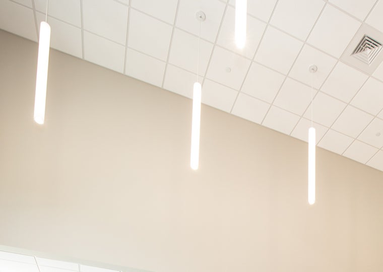 Long skinny lights hang from a ceiling.