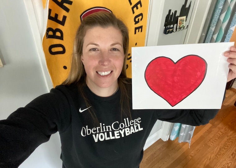 A woman holds a picture of a heart.