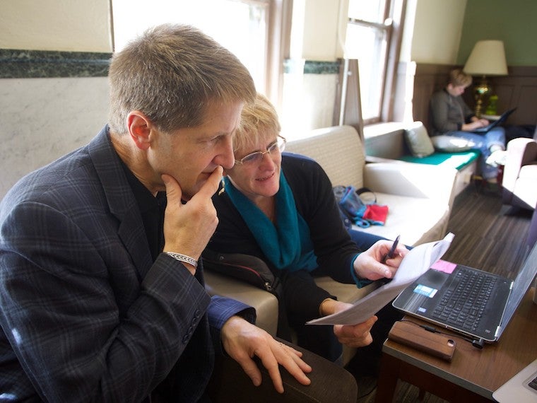 A man and woman look thoughtfully at a sheet of paper.