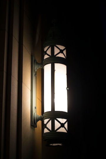 A long black metal wall sconce on a brick building