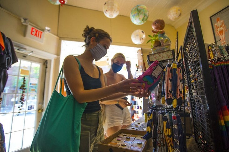 A student wearing a mask browses bags and jewelry at an eclectic shop.