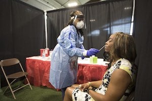 A medical worker administers a nasal swab test to President Ambar.