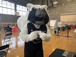 Yeobie mascot holds up a vaccination card.