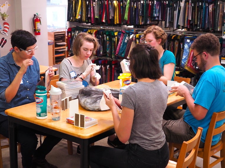 students at table cleaning CD and video cases