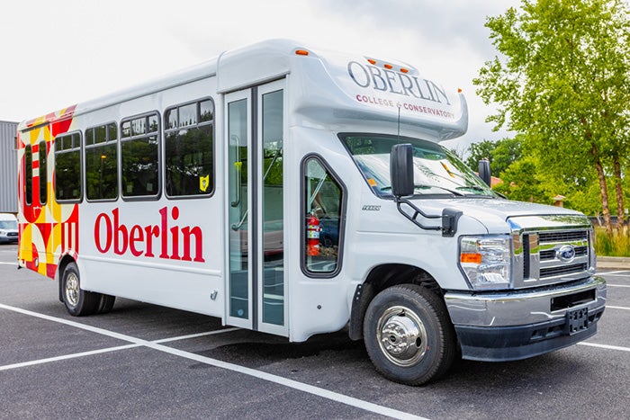 White bus with Oberlin logo and geometric decal covering the side