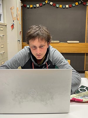 Samuel at a desk, focused on his laptop