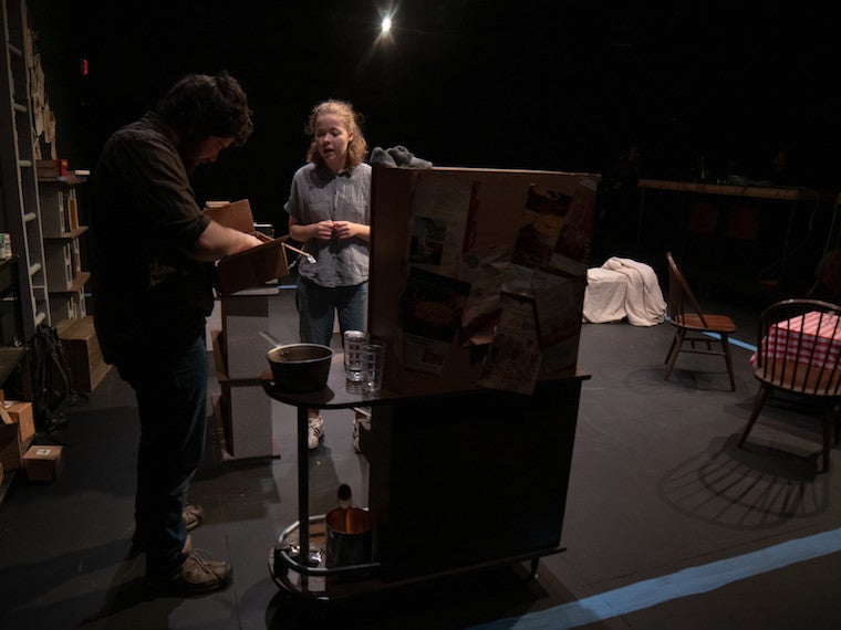 A girl and man work in a kitchen.