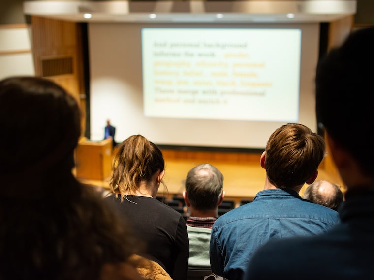 Audience members listen to a man on stage.