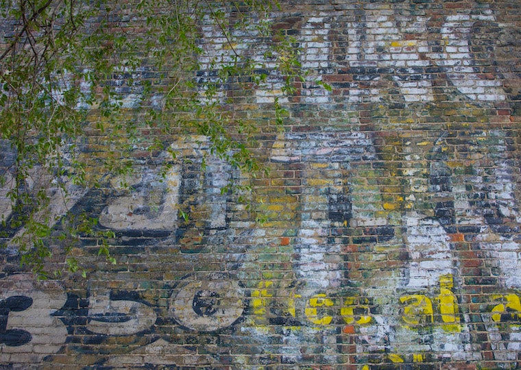 A brick wall with an old advertisement painted on it.