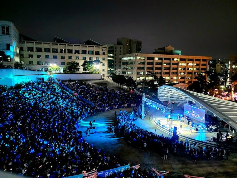 Hanyang University's amphitheater at night, filled with students under fluorescent blue lighting. 
