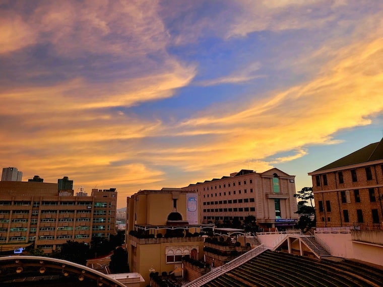 Hanyang University at sunset with cascades of orange and pink clouds.