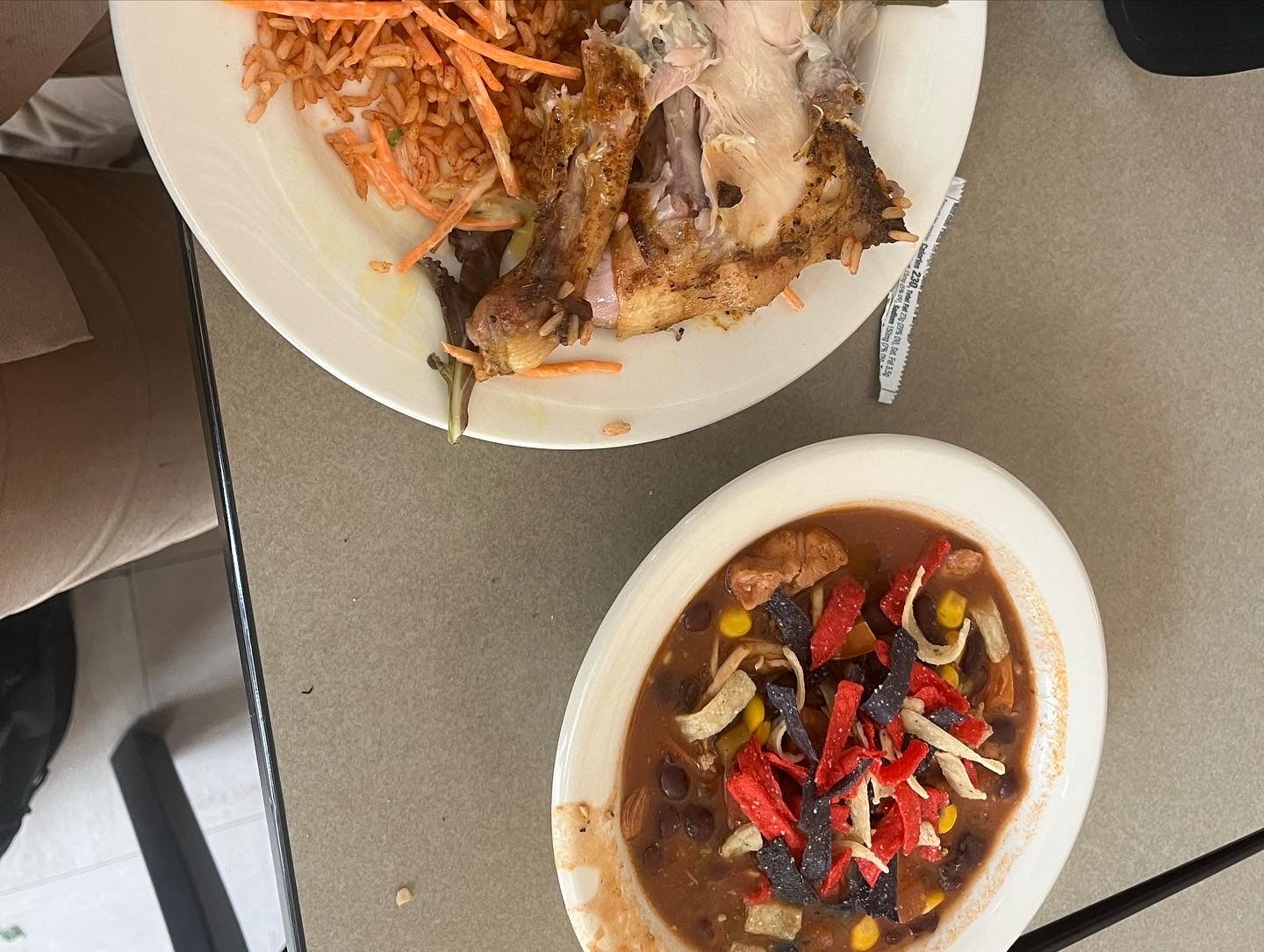 A scrumptious looking bowl of soup next to a half eaten plate of chicken and other meal components from Lord Saunders.