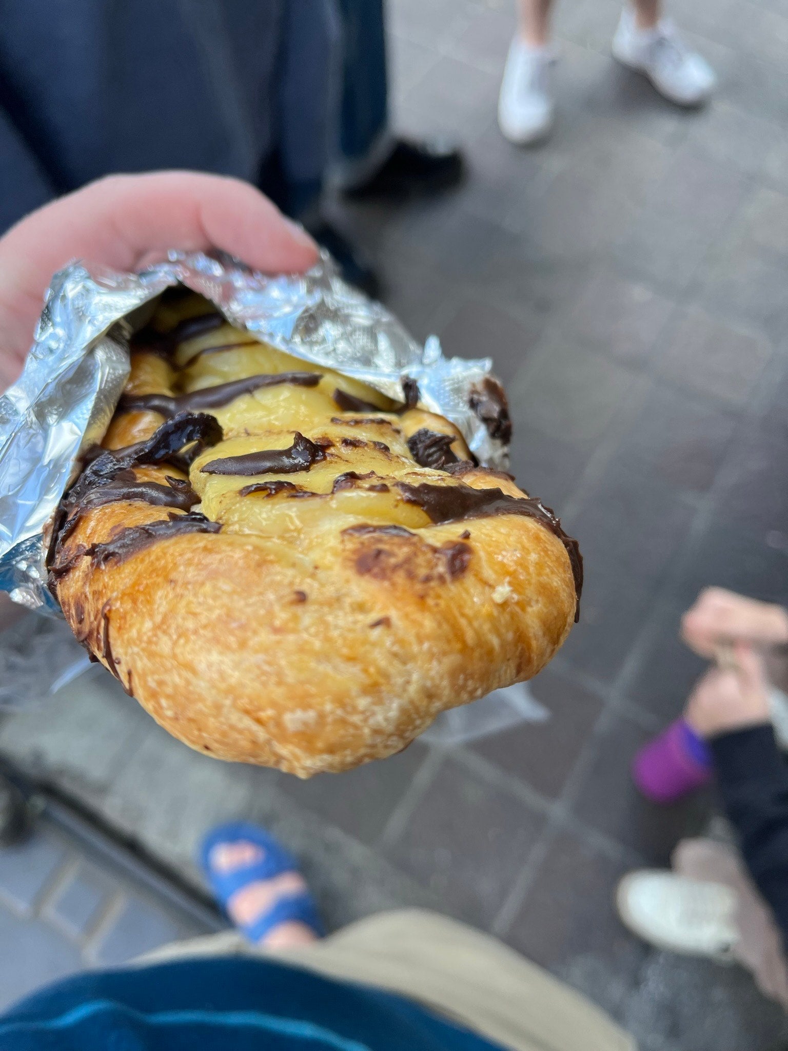 A croissant with chocolate drizzled enticingly on top.