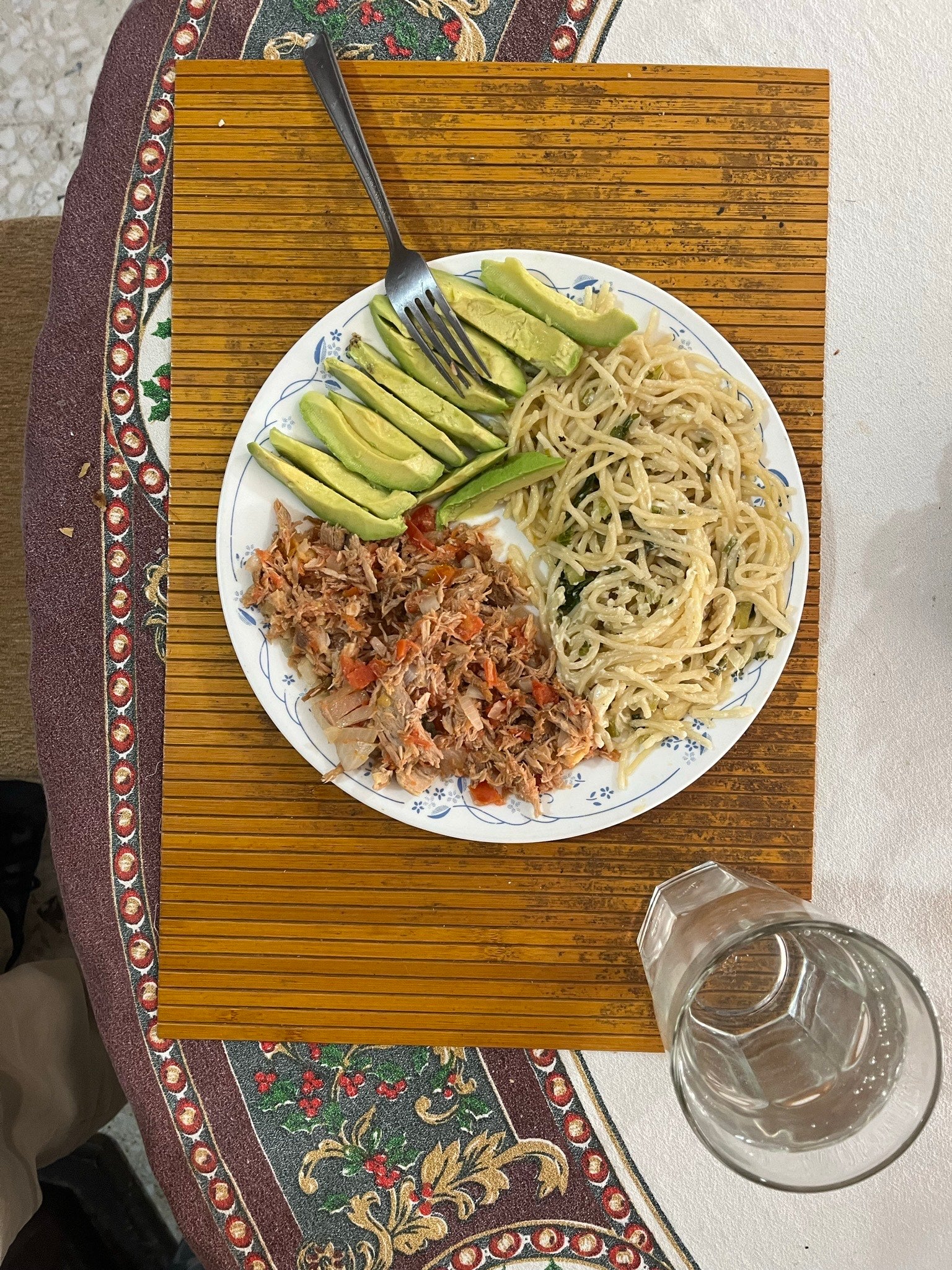 A meal of noodles, minced chicken, and avocado.