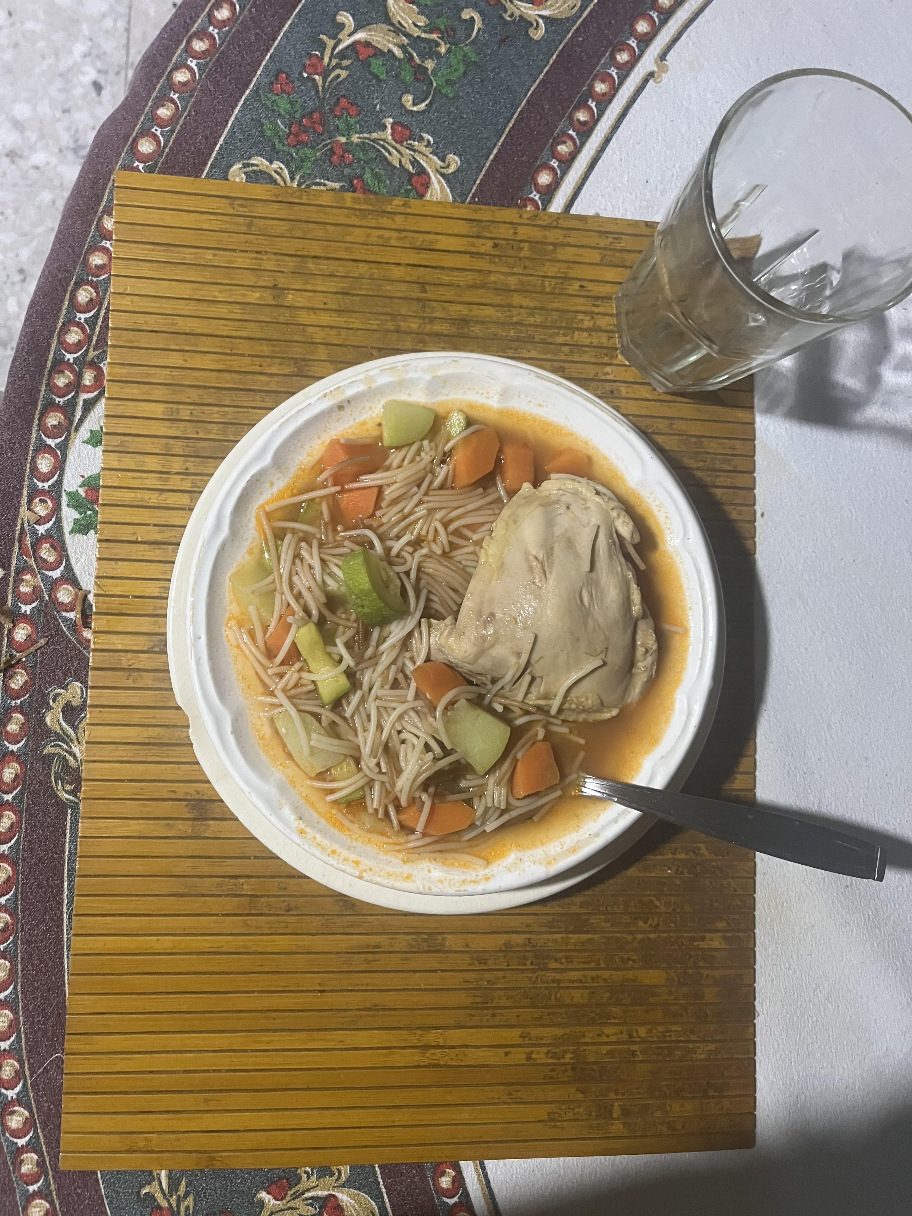 A delicious Mexican soup (called pozole) with a large piece of chicken in it.