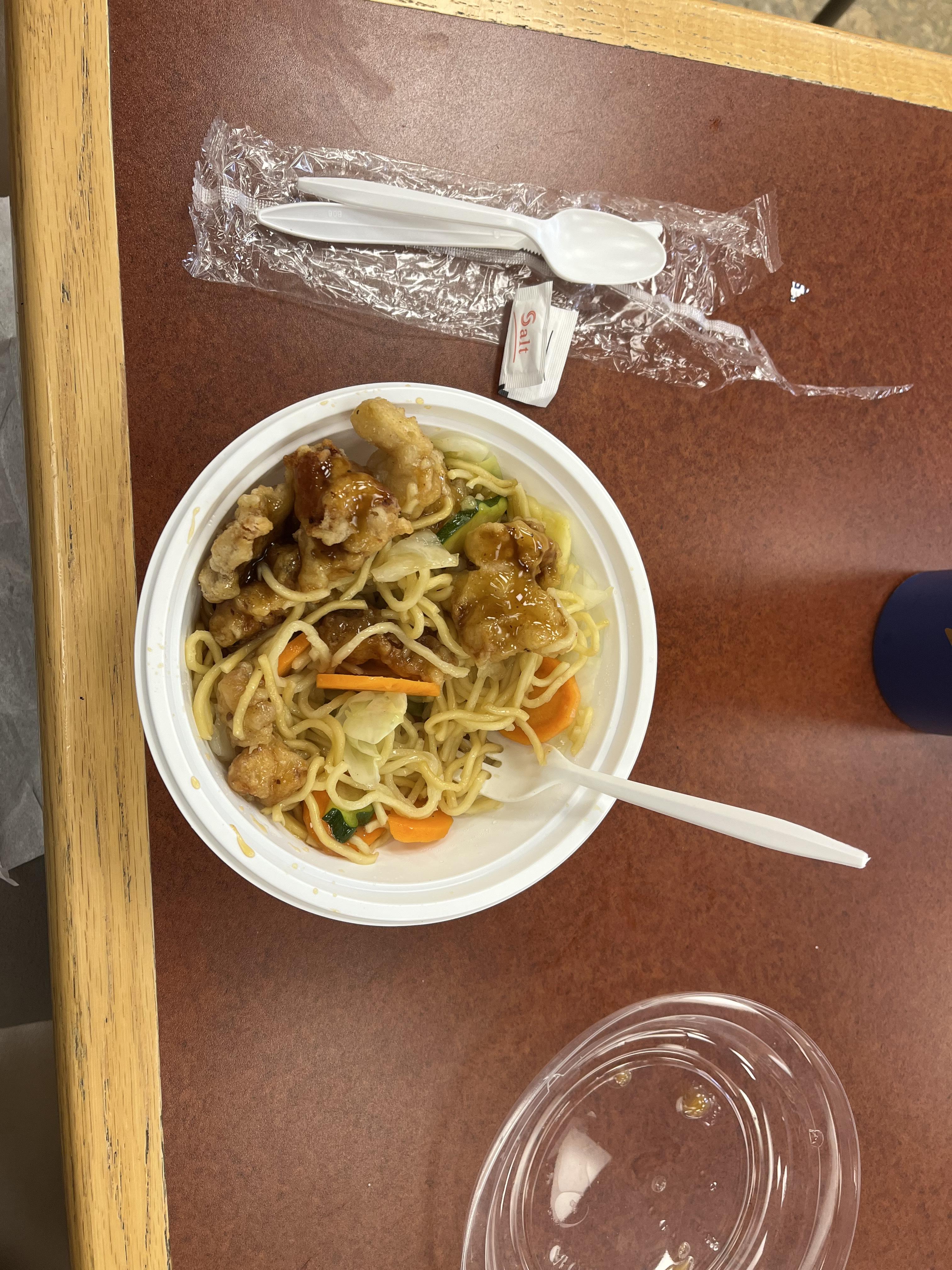A bowl with noodles and orange chicken from Umami.