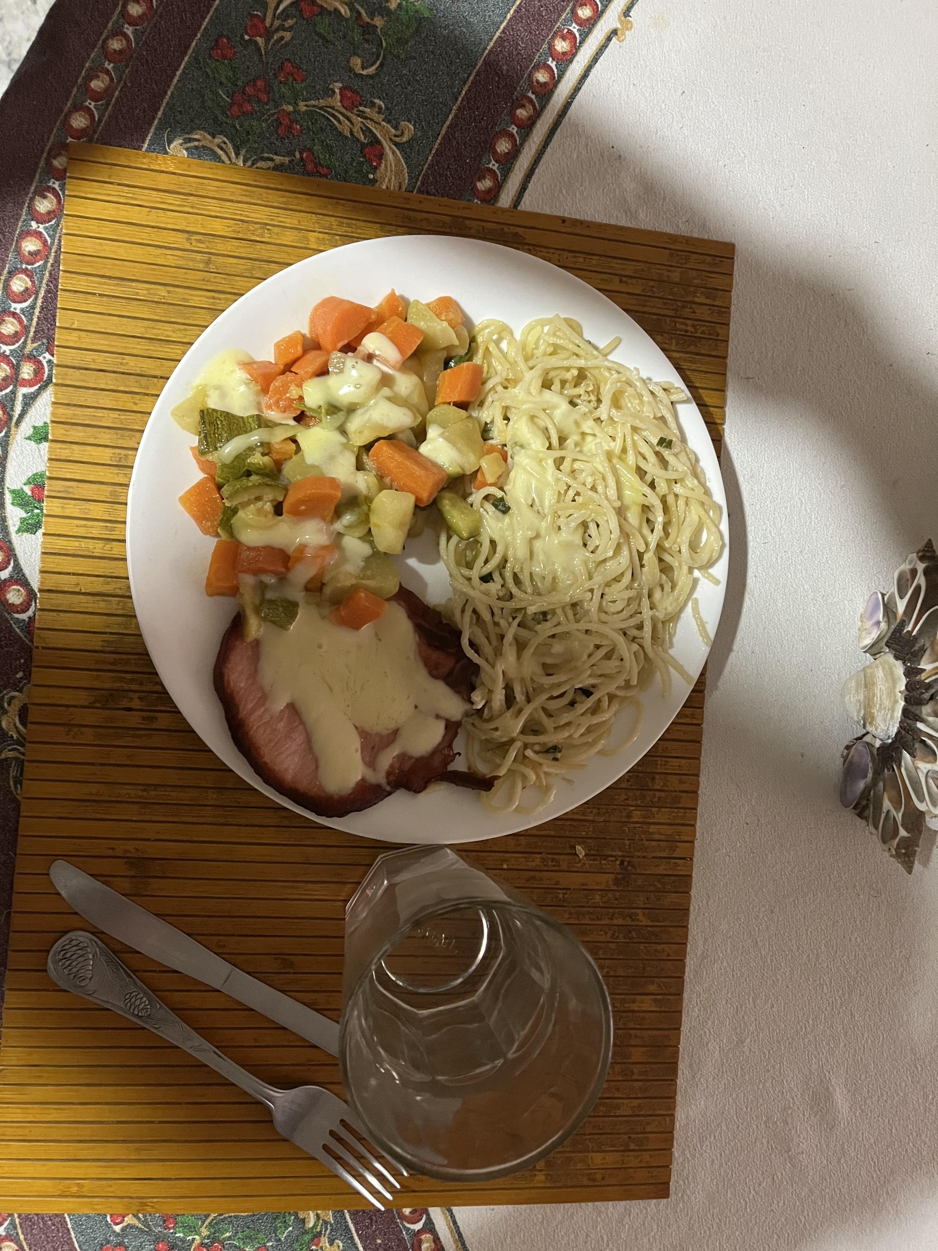 A meal of noodles, vegetables, and pork in a delicious cream sauce.