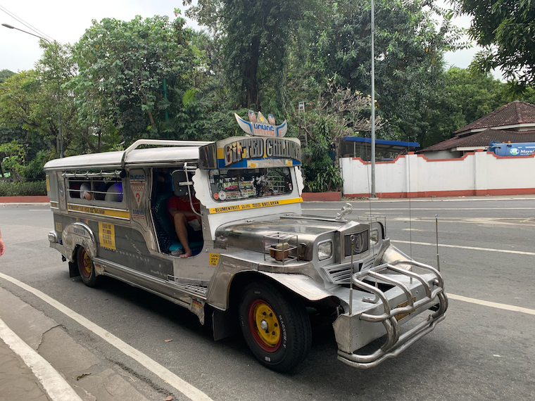 a silver Jeep with the words "Gifted Children" crowded with people on a road