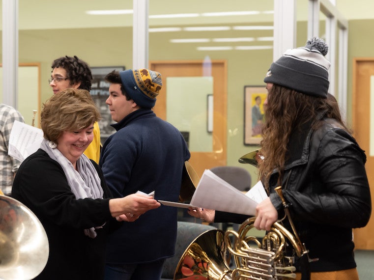 A woman gives a student a sheet of music.