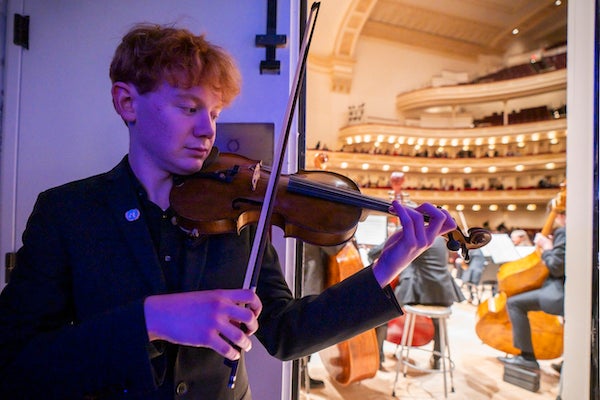 A young man plays the violin backstage.