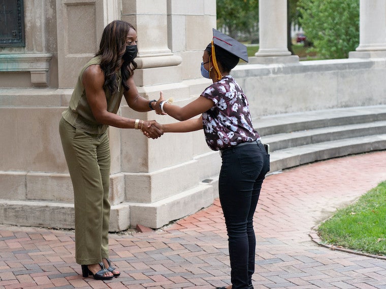 A woman gives a student a scroll.