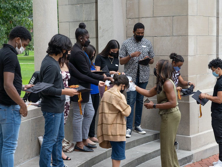 A small group  of students are given graduation caps.