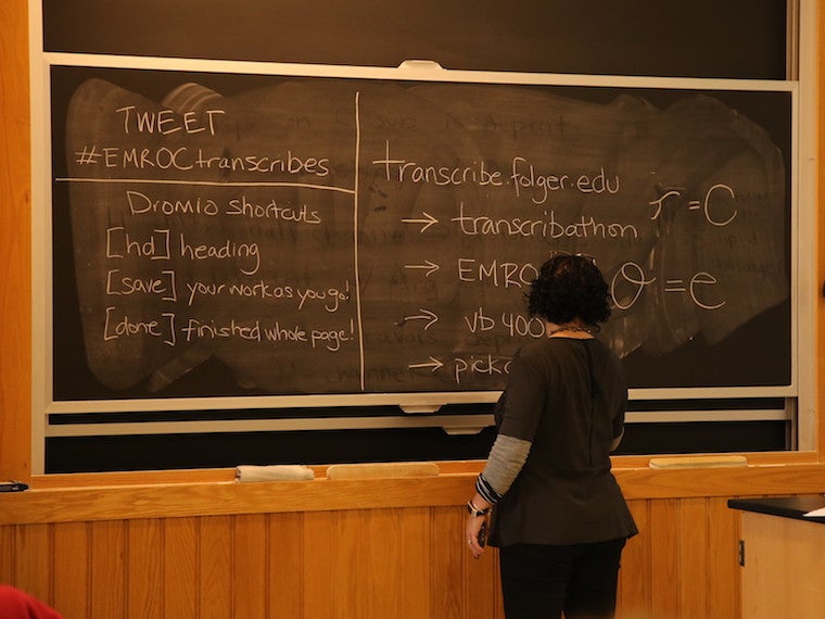 A woman writes on a large chalkboard.