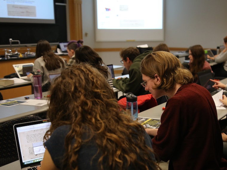 Students sit at desks in a classroom.