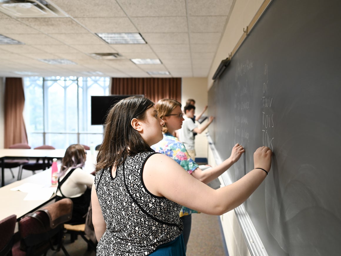 groups of students at a blackboard while teacher looks on
