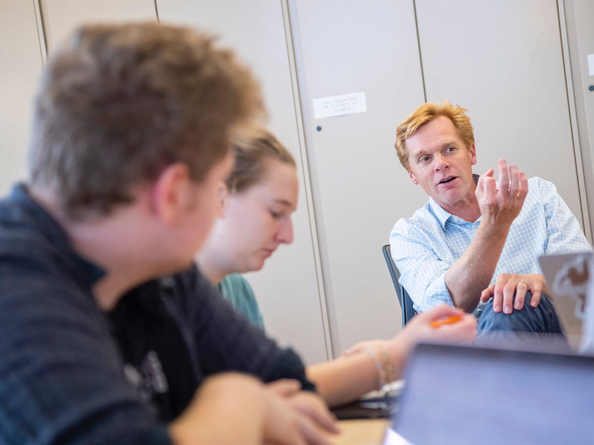 male professor discussing a course with two of his students.