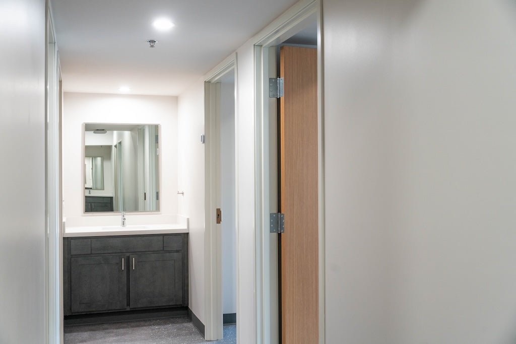 Photo of suite's sink at the end of the hallway with mirror, counter space, and storage