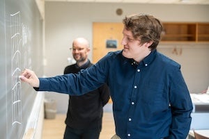 Student writing on chalkboard.