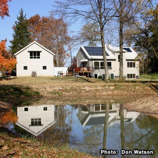 A house with solar panels is reflected in water