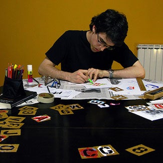 Christopher at a table with letter stencils, papers, and markers