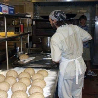 A man takes loaves out of a large oven