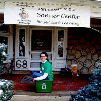 David sits in a recycling bin on the steps of the Bonner Center for Community-Engaged Learning, Teaching, and Research
