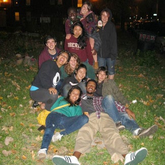 A group of friends at night, some of them sprawled on the grass