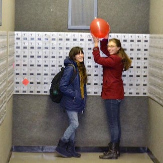 Jocie and a friend find a balloon by a wall of post office boxes