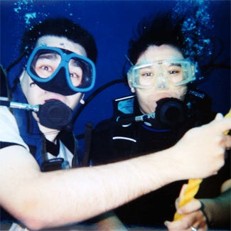 Two scuba divers underwater, bubbles rising from their masks
