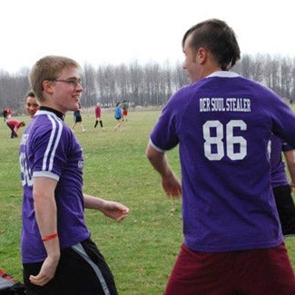 Soccer players on the sidelines. One wears a short with number 86 and the name Der Soul Stealer.