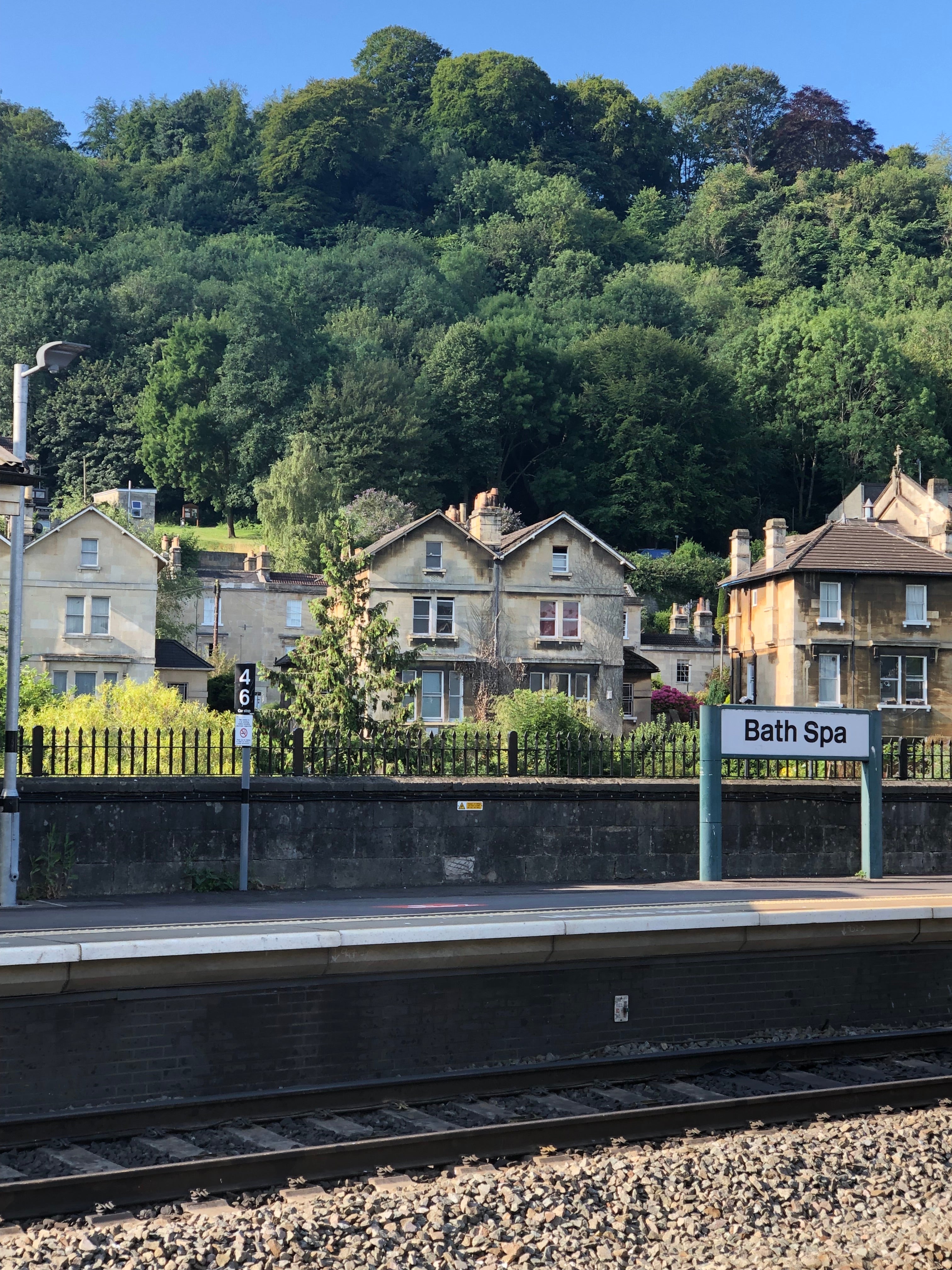  A view of the train platform at Bath Spa with houses and a hillside in the background.