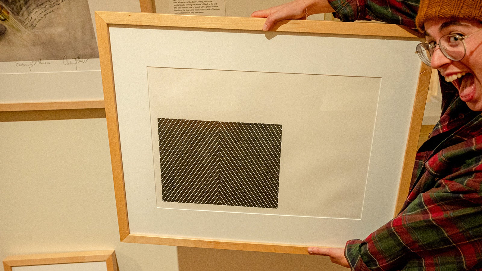 An excited student holds up a piece of framed art.