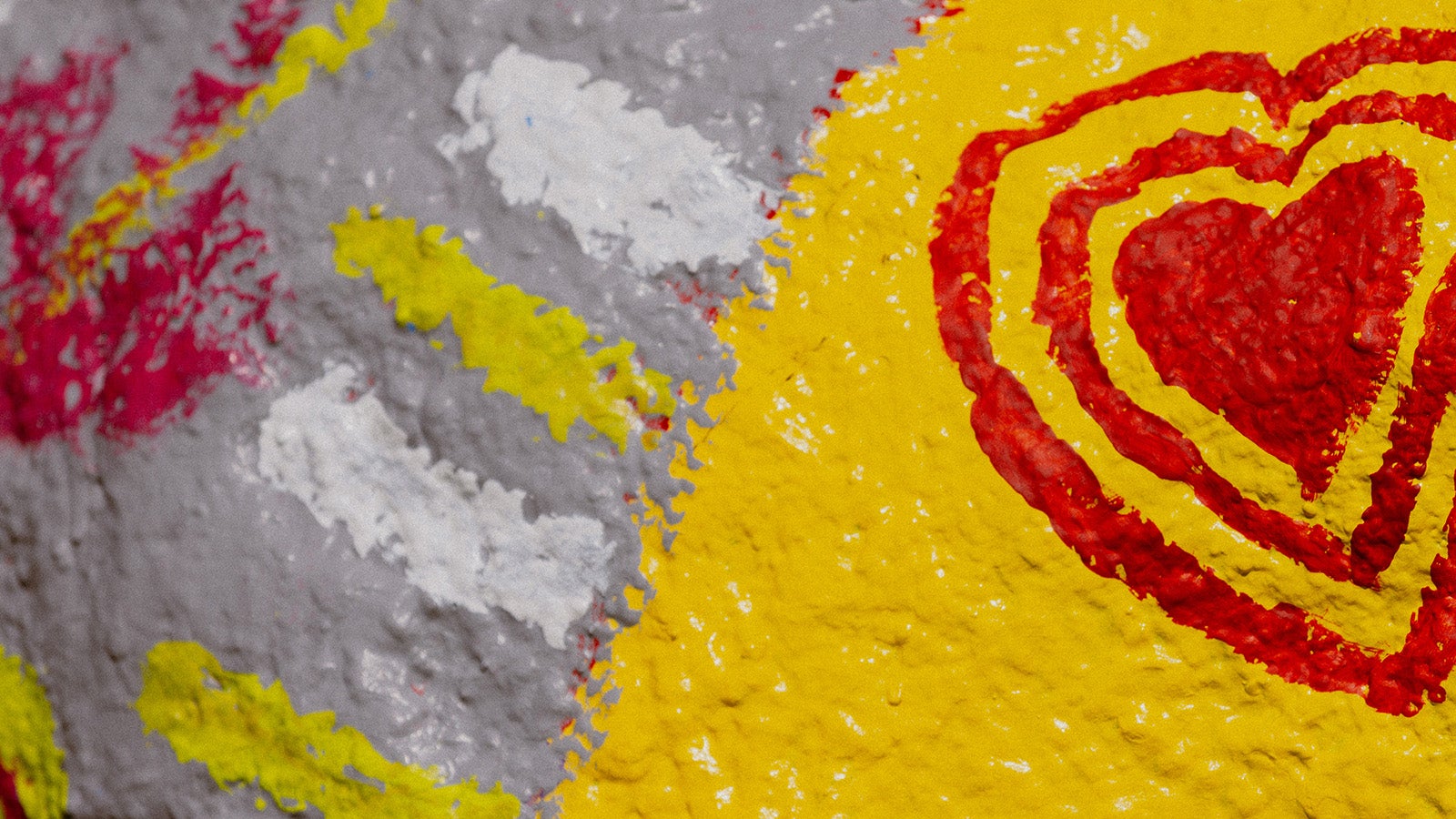 Close-up of brightly colored, painted hearts on a large rock.